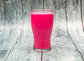 rose milk served in glass isolated on wooden table top view of indian healthy drink photo