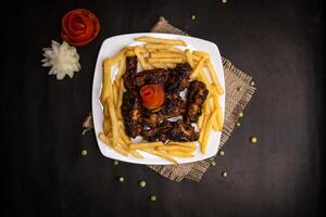 chicken bbq wings with fries served in dish isolated on napkin mat top view of fastfood food photo