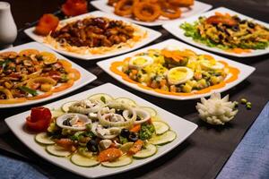 Assorted salads variety with chicken vegetable cashew nut salad, classic Greece salad, russian salad, grilled chicken salad, munchies and fried onion rings served isolated side view of healthy food photo