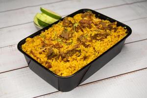 beef khichuri biryani rice pulao with cucumber and lemon slice served in dish isolated on wooden table closeup side view of bangladeshi and indian spices lunch food photo