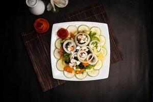 classic Greece salad with cucumber, onion, tomato, olive, carrot and feta cheese served in dish isolated on napkin mat top view of healthy supper food photo