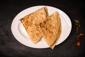 paratha rebanado servido en plato aislado en oscuro antecedentes parte superior ver indio especias, bangladeshi y pakistaní comida foto