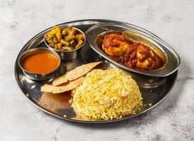 Boiled egg biryani thali set with gravy, mixed vegetable of aloo gobi matar, nachos and shorba served in dish isolated on background top view of indian spicy food photo