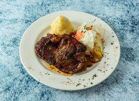 grilled beef steak with mashed potato and egg served in plate isolated on background top view of italian food photo