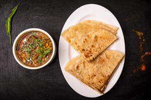 paratha con dal chana o chanay servido en plato aislado en oscuro antecedentes parte superior ver indio especias, bangladeshi y pakistaní comida foto