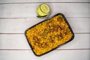 beef khichuri biryani rice pulao with cucumber and lemon slice served in dish isolated on wooden table top view of bangladeshi and indian street food photo