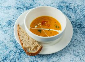 pumpkin soup with bread served in bowl isolated on background top view of italian food photo