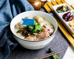 carne de vaca pescado sopa pescado udon servido en cuenco con palillos y Adición bandera aislado en servilleta lado ver de japonés comida en mesa foto