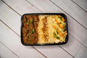 Beef Bhuna with pulao biryani rice with cucumber, dip sauce and lemon slice served in dish isolated on wooden table top view closeup of bangladeshi and indian spicy lunch food photo