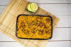 beef khichuri biryani rice pulao with cucumber and lemon slice served in dish isolated on wooden table top view of bangladeshi and indian spicy lunch food photo