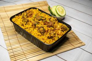 beef khichuri biryani rice pulao with cucumber and lemon slice served in dish isolated on wooden table side view of bangladeshi and indian spicy lunch food photo