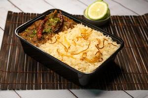 Achari beef pulao biryani rice with cucumber and lemon slice served in dish isolated on wooden table side view of bangladeshi and indian spicy lunch food photo