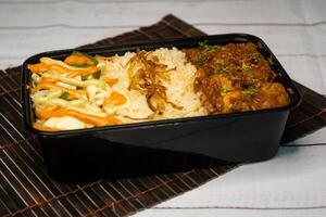 Chicken Bhuna with pulao biryani rice with cucumber, dip sauce and lemon slice served in dish isolated on wooden table side view closeup of bangladeshi and indian spicy lunch food photo