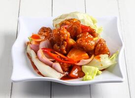 sweet and sour pork with tomato and onion served in dish isolated on table top view of singapore food photo