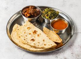 Carne de cordero korma thali conjunto con mezclado vegetal de aloo palak, shorba, nachos y chapati servido en plato aislado en antecedentes parte superior ver de indio picante comida foto