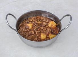 Aloo keema or minced meat with potato served in karahi isolated on grey background side view of pakistani and indian spices food photo