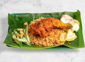 Hyderabadi fried chicken biriyani rice or pulao with salad served in dish isolated on banana leaf top view of singapore food photo