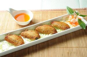 Vietnamese Lemongrass Chicken Wings with chilli sauce served in dish isolated of table top view fast food snacks photo