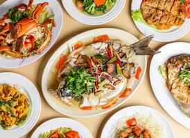 steamed black mullet fish, steamed crab, stir fried broccoli wuth mushroom, fragrant fried chicken, salted egg squid, teochew pomfret, sweet sour and pork yamring top view singapore sea food variety photo