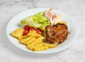 grilled chicken chop with lemon, salad, tomato and dip served in dish isolated on banana leaf top view of singapore food photo