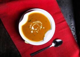 Lentils Soup with spoon served in dish isolated on red mat top view on table arabic food photo