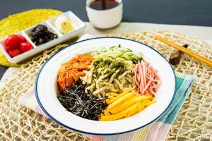 frío tallarines con salsa, Pepino y tomate servido en plato con palillos y Adición bandera aislado en servilleta lado ver de japonés comida en mesa foto