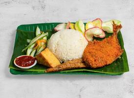 fish penyet with rice, salad and chilli sauce served in dish isolated on banana leaf top view of singapore food photo