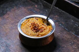 Mathrooba Chicken haleem, halim with fried onion served in dish isolated on red mat top view on table arabic food photo