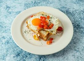 english blet sunny side up egg sandwich topping with tomato served in plate isolated on background top view of italian food photo