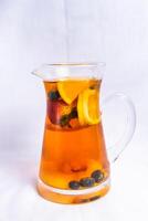 Fruit black tea include lemon slice, strawberry and blueberry served in jar isolated on background side view of iced drink photo