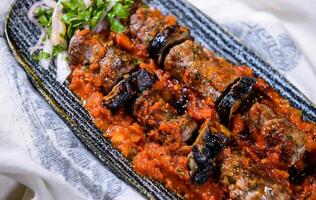 meat kebab with eggplant, mashed tomato sauce and onion served in dish isolated on food table top view of middle east spices photo