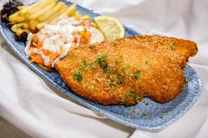 Chicken Escalope with french fries, lemon and salad served in dish isolated on food table top view of middle east spices photo