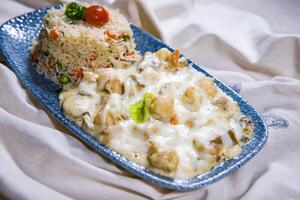 Chicken Bechamel Sauce or white sauce with vegetable fried rice served in dish isolated on food table top view of middle east spices photo