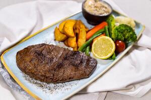 Beef fillet steak with fried veggies, salad, lemon and dip served in dish isolated on food table top view of middle east spices photo