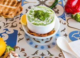 Broccoli Soup with lemon, crackers, spoon and bell pepper served in dish isolated on table top view of arabic food photo