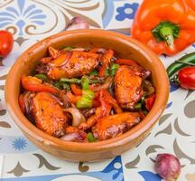 Fakhara Chicken Wings with tomato, onion and bell pepper served in dish isolated on table top view of arabic food photo