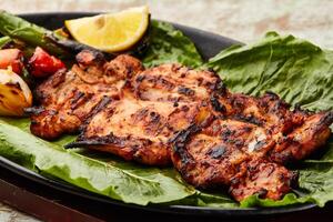 Grilled Chicken with lemon slice and tomato served in dish isolated on table top view of arabic food photo