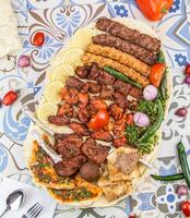 Assorted mix grills with tikka boti seekh kabab of lamb chops, pita bread, flafel, chicken, beef, lamb, mutton bbq platter served in dish isolated on table top view of arabic food photo