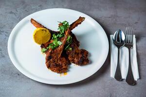 Grilled Lamb Chop with lemon slice and spoon served in dish isolated on grey background top view of bahrain food photo