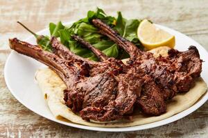 Grilled Lamb Chops with lemon slice ad salad served in dish isolated on table top view of arabic food photo