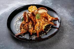 Grilled prawns with dip and lemon slice served in dish isolated on background top view of seafood grill photo