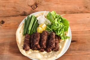 Swek Of Beef Kebab or meat kabab with bahraini bread tandoori nan, lime and salad served in dish isolated on wooden table top view middle eastern grills food photo