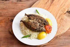 Safi Fish fry with White Rice, tomato and lime served in dish isolated on wooden table top view middle eastern lunch food photo