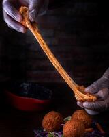 queso pelotas participación en mano con aderezo, cebolla, Zanahoria y lechuga hoja servido en plato aislado en de madera mesa lado ver de Arábica comida foto