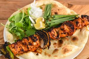 Shish Tawook kebab with bahraini bread tandoori nan, lime and salad served in dish isolated on wooden table top view middle eastern grills food photo