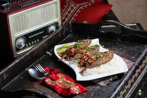 safi shilani or fried fish with rice served in dish isolated on red mat top view on table arabic food photo