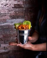 Dynamite Shrimp Bucket holding in hand with say sauce, lemon slice and lettuce leaves served side view of arabic food photo