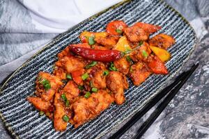 peking style chilli chicken with spring onion and tomato served in dish isolated on food table top view of middle east spices photo