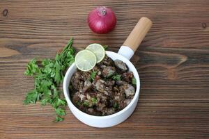 Spicy Chicken liver with onion, coriander and lemon slice served in dish isolated on table side view of arabic food photo