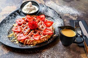 Crusted Strawberry waffle with white chocolate, whipped cream, pistachio, knife and fork served in dish isolated on dark background top view cafe dessert food photo